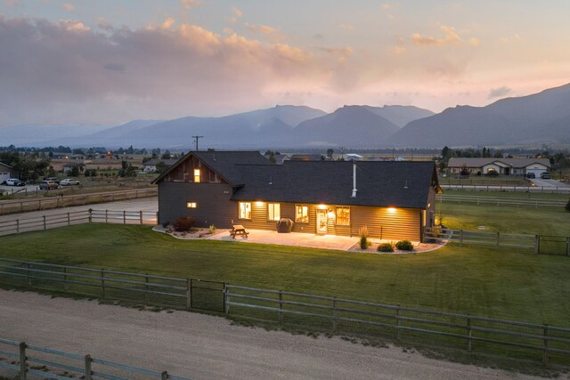 4416 Gem Ranch Rd, Stevensville, MT 59870 - back of property at dusk featuring a patio, a mountain view, a view of rural / pastoral area, and a fenced backyard