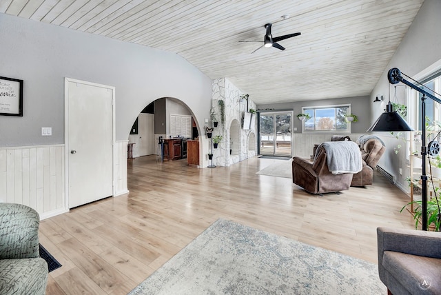 living room featuring arched walkways, lofted ceiling, wood finished floors, wood ceiling, and wainscoting