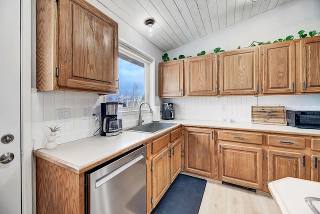 kitchen featuring tasteful backsplash, lofted ceiling, light countertops, stainless steel dishwasher, and a sink