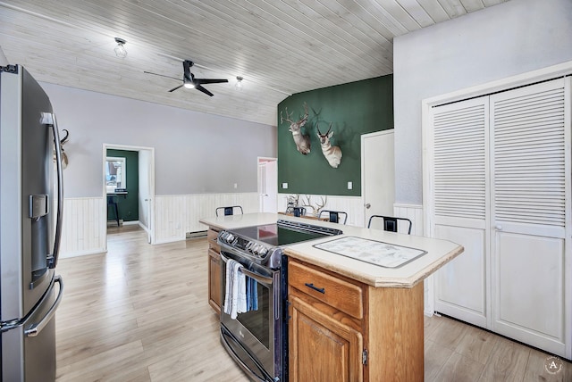 kitchen featuring light countertops, wainscoting, stainless steel fridge, and electric range oven