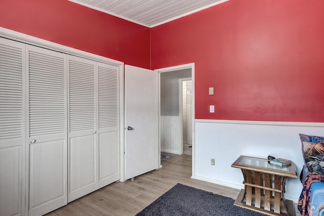 bedroom featuring wainscoting, a closet, and light wood-type flooring