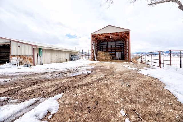 snow covered structure with an exterior structure, a pole building, a carport, and an outdoor structure