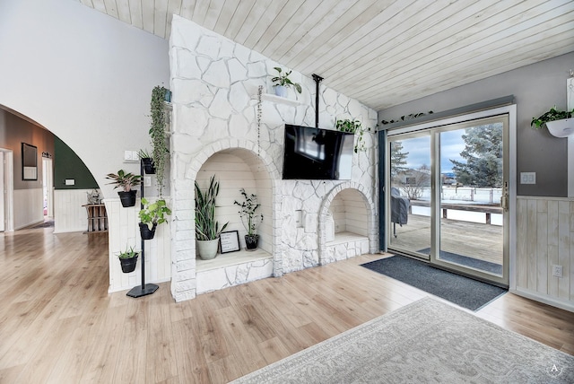 living room featuring arched walkways, lofted ceiling, wainscoting, wood finished floors, and wooden ceiling