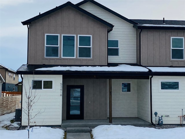 view of front of home featuring covered porch, central AC, board and batten siding, and fence