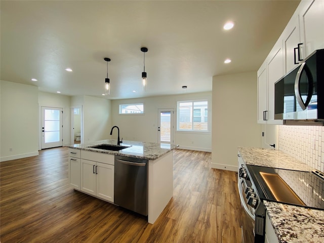 kitchen with appliances with stainless steel finishes, open floor plan, a sink, and dark wood-style floors