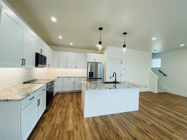 kitchen featuring appliances with stainless steel finishes, a sink, tasteful backsplash, white cabinetry, and light stone countertops