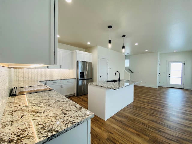 kitchen with dark wood finished floors, stainless steel refrigerator with ice dispenser, backsplash, a sink, and light stone countertops