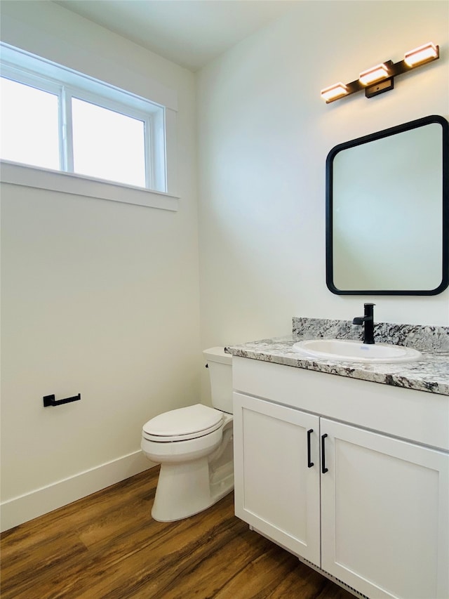 bathroom featuring baseboards, vanity, toilet, and wood finished floors