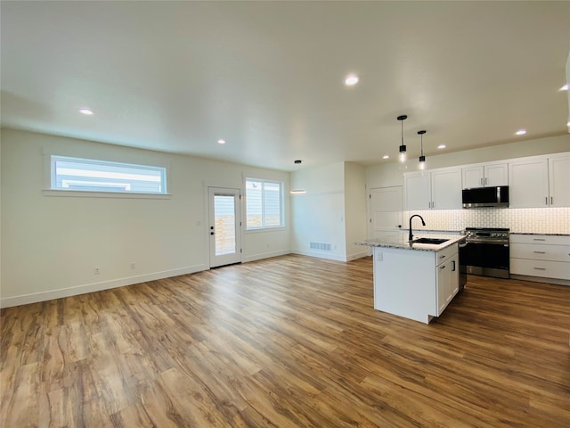 kitchen featuring visible vents, open floor plan, wood finished floors, stainless steel appliances, and a sink