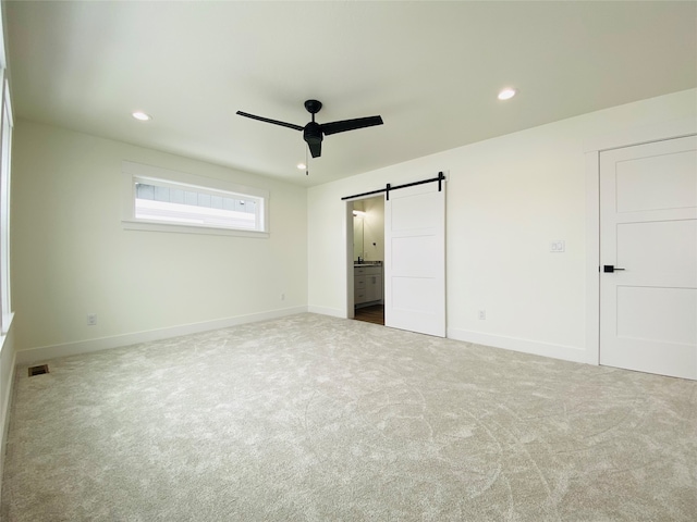 unfurnished bedroom featuring carpet, baseboards, recessed lighting, and a barn door