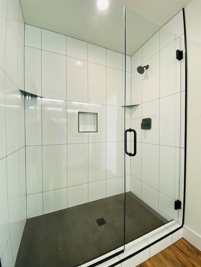 bathroom featuring wood finished floors and a shower stall