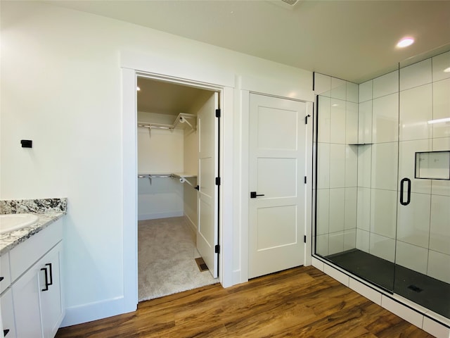 full bath with a shower stall, a spacious closet, wood finished floors, and vanity