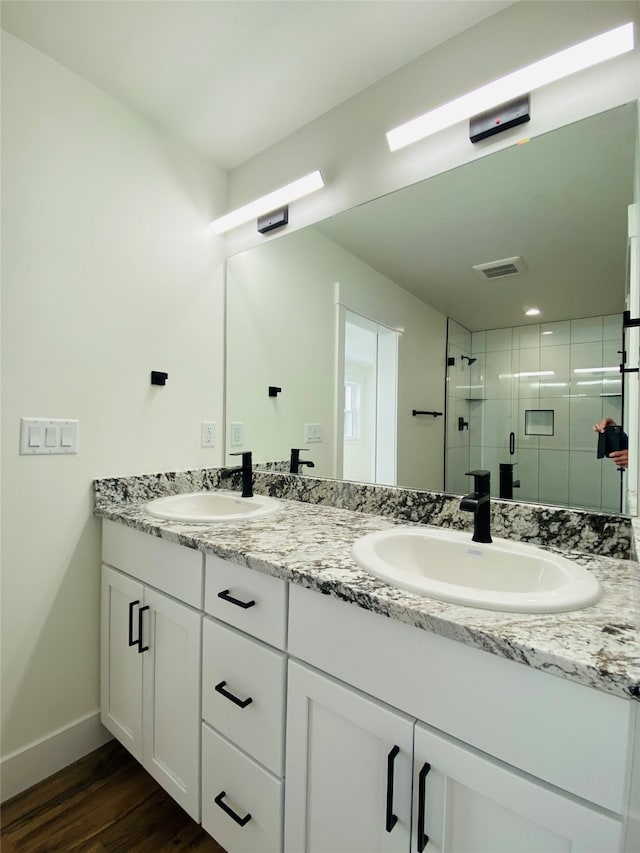 full bath featuring double vanity, wood finished floors, a stall shower, and a sink