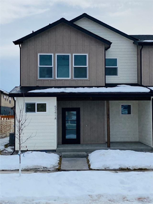 view of front facade featuring a porch, board and batten siding, and cooling unit