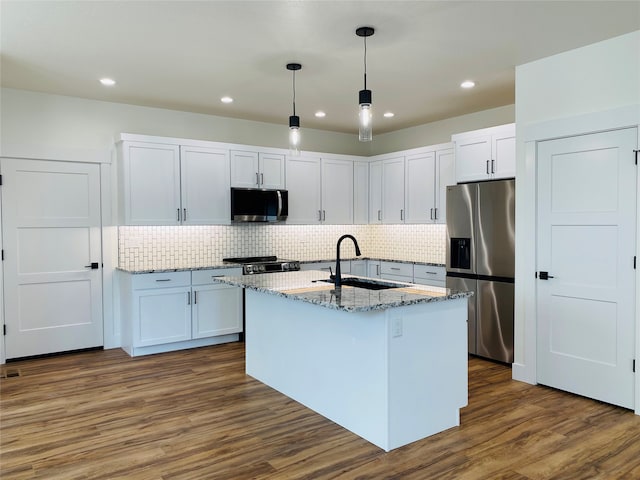 kitchen featuring light stone counters, stainless steel appliances, dark wood-style flooring, a sink, and decorative light fixtures