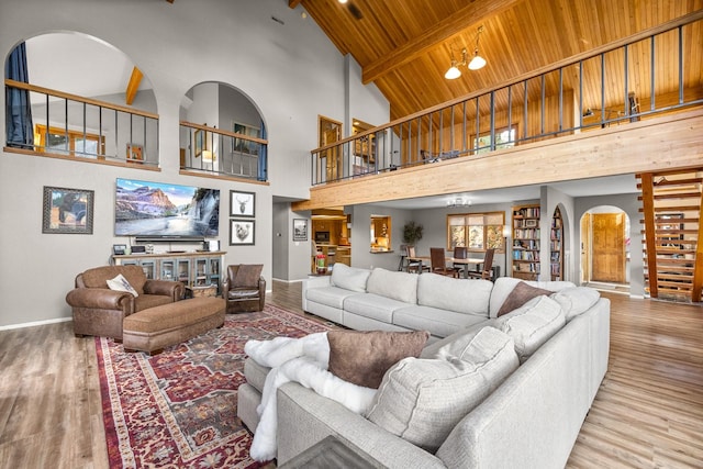 living room featuring arched walkways, wooden ceiling, wood finished floors, baseboards, and beamed ceiling