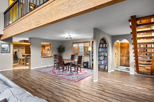 dining space with arched walkways, stairway, wood finished floors, and baseboards