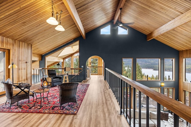 living area featuring a water view, an upstairs landing, wood finished floors, high vaulted ceiling, and beamed ceiling