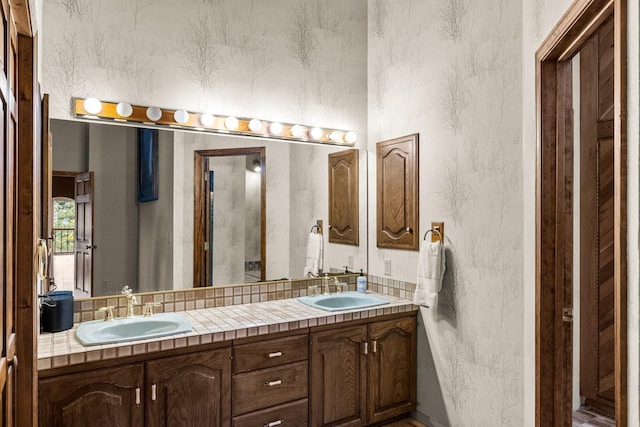 full bath with double vanity, a sink, and a textured wall