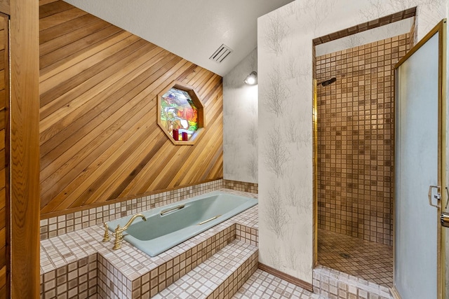 bathroom with a bath, wood walls, a shower stall, and visible vents