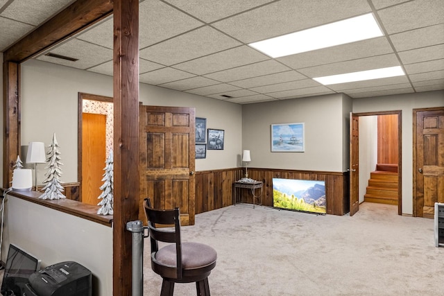 office area with carpet floors, wood walls, wainscoting, and a paneled ceiling