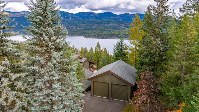 aerial view featuring a wooded view and a water and mountain view