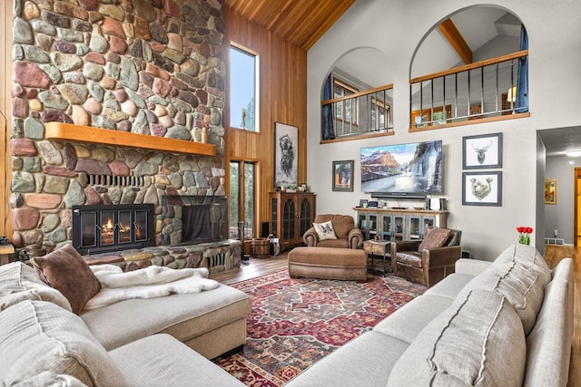 living area featuring high vaulted ceiling, wooden ceiling, a fireplace, and wood finished floors