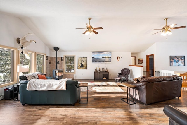 living room featuring a wood stove, vaulted ceiling, and a ceiling fan