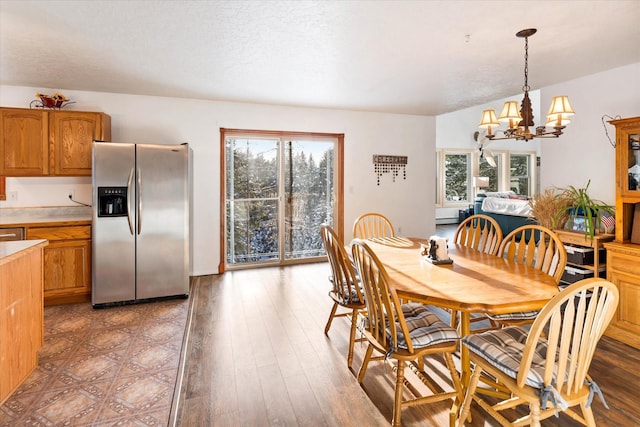 dining room with a textured ceiling, light wood-type flooring, a wealth of natural light, and an inviting chandelier