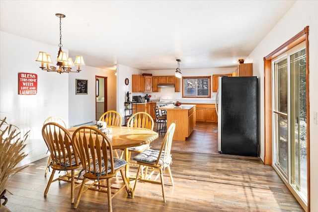 dining area featuring a notable chandelier, baseboards, and wood finished floors