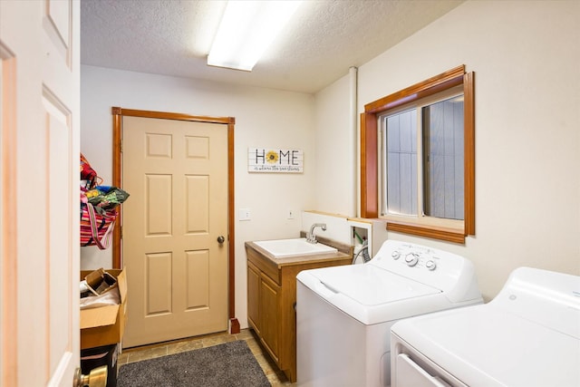 washroom featuring washing machine and dryer, cabinet space, a sink, and a textured ceiling