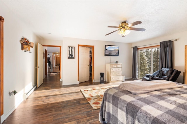 bedroom with baseboards, a baseboard heating unit, ceiling fan, and wood finished floors