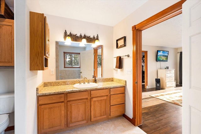 full bathroom featuring toilet, baseboards, wood finished floors, and vanity