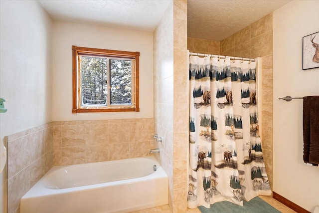 bathroom featuring a tub, curtained shower, a textured ceiling, and baseboards