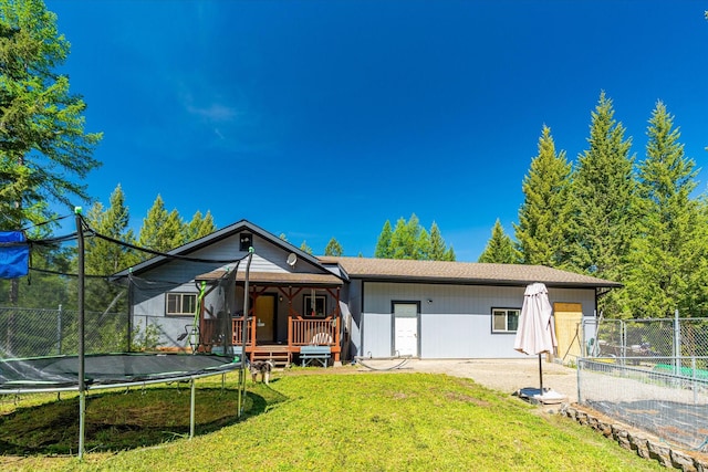 view of front of house with a trampoline, a front yard, and fence