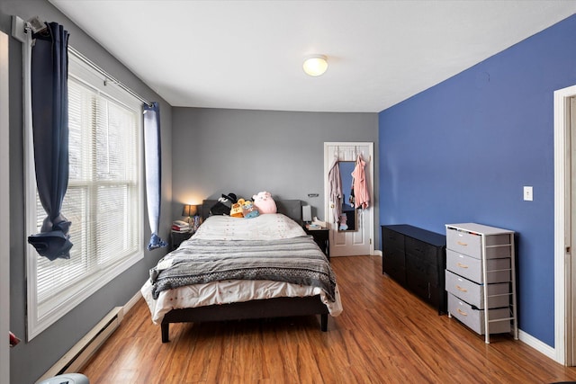 bedroom featuring baseboards, baseboard heating, and wood finished floors