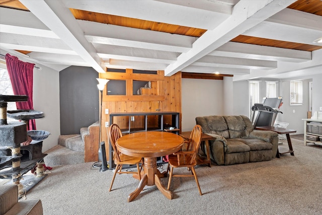 carpeted dining area featuring beamed ceiling and stairway