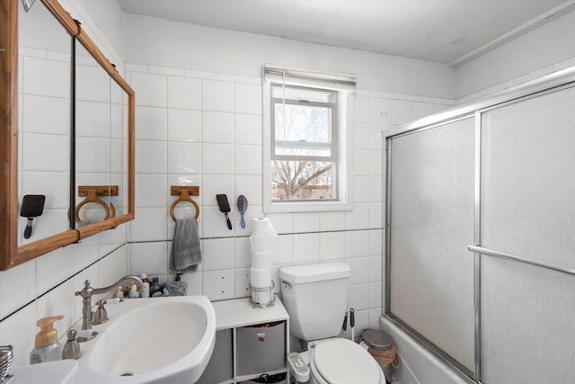 bathroom featuring toilet, tile walls, backsplash, and a sink