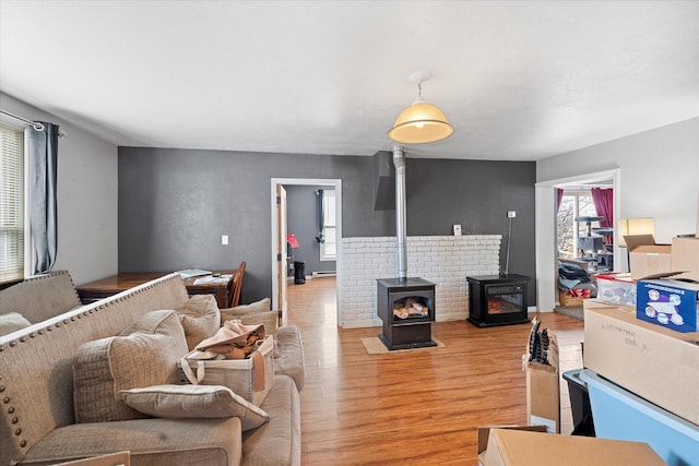 living room featuring baseboard heating, a wood stove, and light wood-style floors