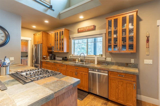 935 Pack Rat Ln, Whitefish, MT 59937 - kitchen with stainless steel appliances, recessed lighting, glass insert cabinets, light wood-style flooring, and brown cabinetry