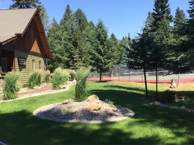 view of yard with a tennis court and fence