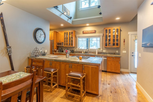 935 Pack Rat Ln, Whitefish, MT 59937 - kitchen with stainless steel appliances, a peninsula, brown cabinetry, a sink, and light wood finished floors