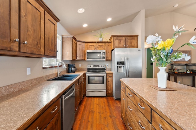 kitchen with lofted ceiling, dark wood-style flooring, a sink, appliances with stainless steel finishes, and brown cabinetry