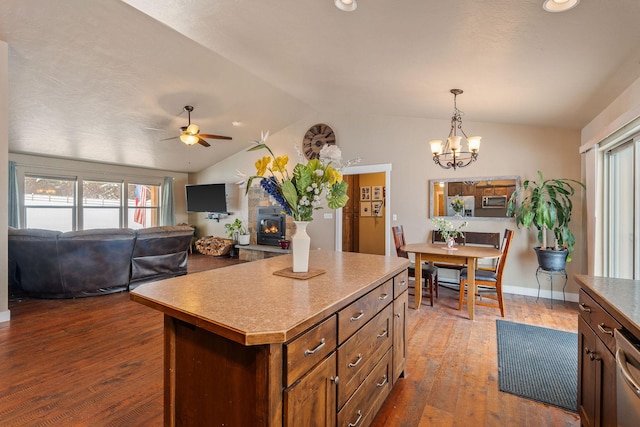 kitchen featuring a glass covered fireplace, vaulted ceiling, dark wood-type flooring, and ceiling fan with notable chandelier