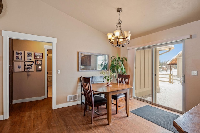 dining room with lofted ceiling, a chandelier, wood finished floors, visible vents, and baseboards