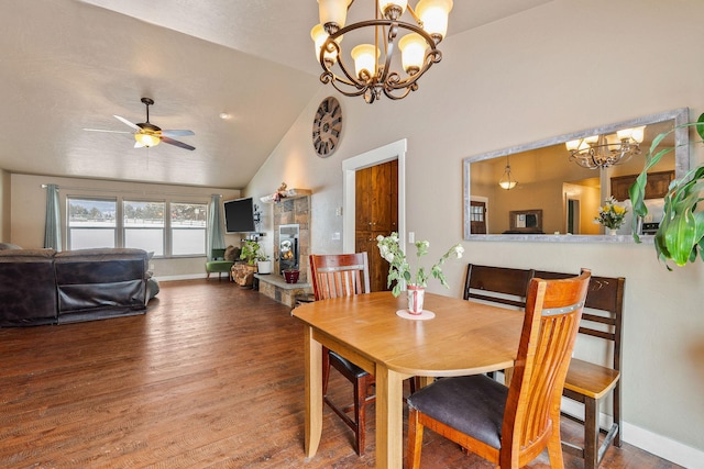 dining area with baseboards, lofted ceiling, wood finished floors, a fireplace, and ceiling fan with notable chandelier