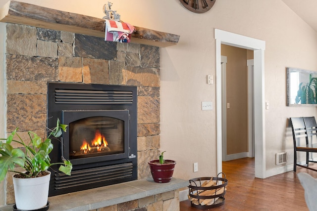 room details featuring baseboards, visible vents, wood finished floors, and a glass covered fireplace