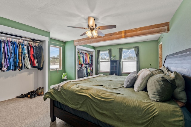 bedroom featuring ceiling fan, multiple windows, carpet, and beam ceiling