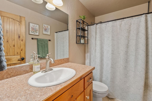 full bathroom featuring a textured wall, vanity, and toilet