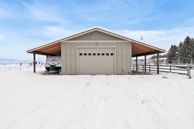 snow covered garage with a garage and fence